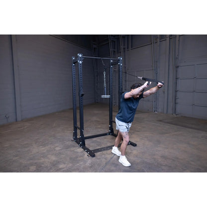 Man using a black cable machine for exercise in a gym.