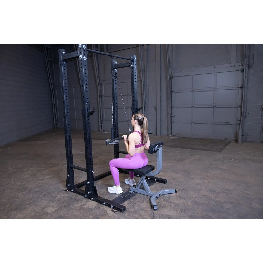 Woman in pink workout gear using a black cable machine in a gym for strength training.