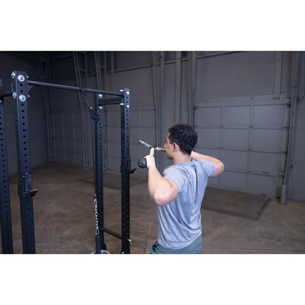 Man using a cable machine for a back workout in a gym.