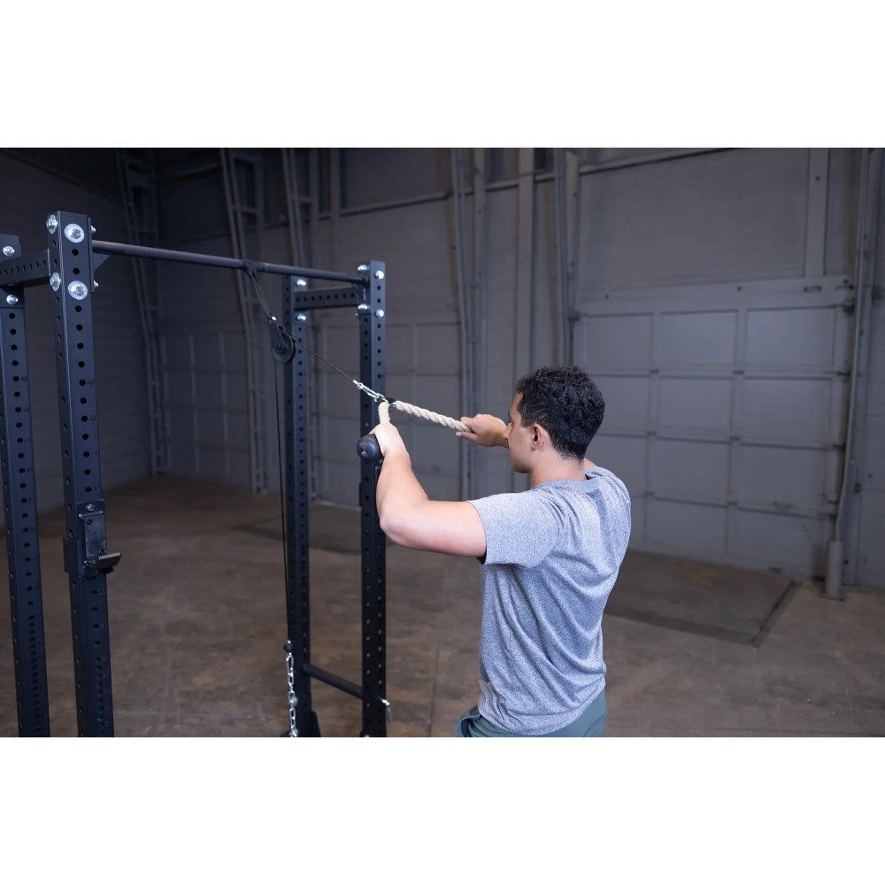 Man using a home gym cable machine with a rope attachment for tricep exercises.