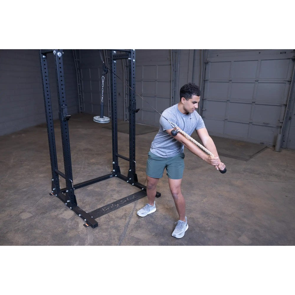 Man performing rope exercise on a cable machine for strength training in a gym.