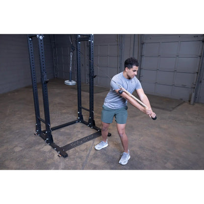 Man performing rope exercise on a cable machine for strength training in a gym.