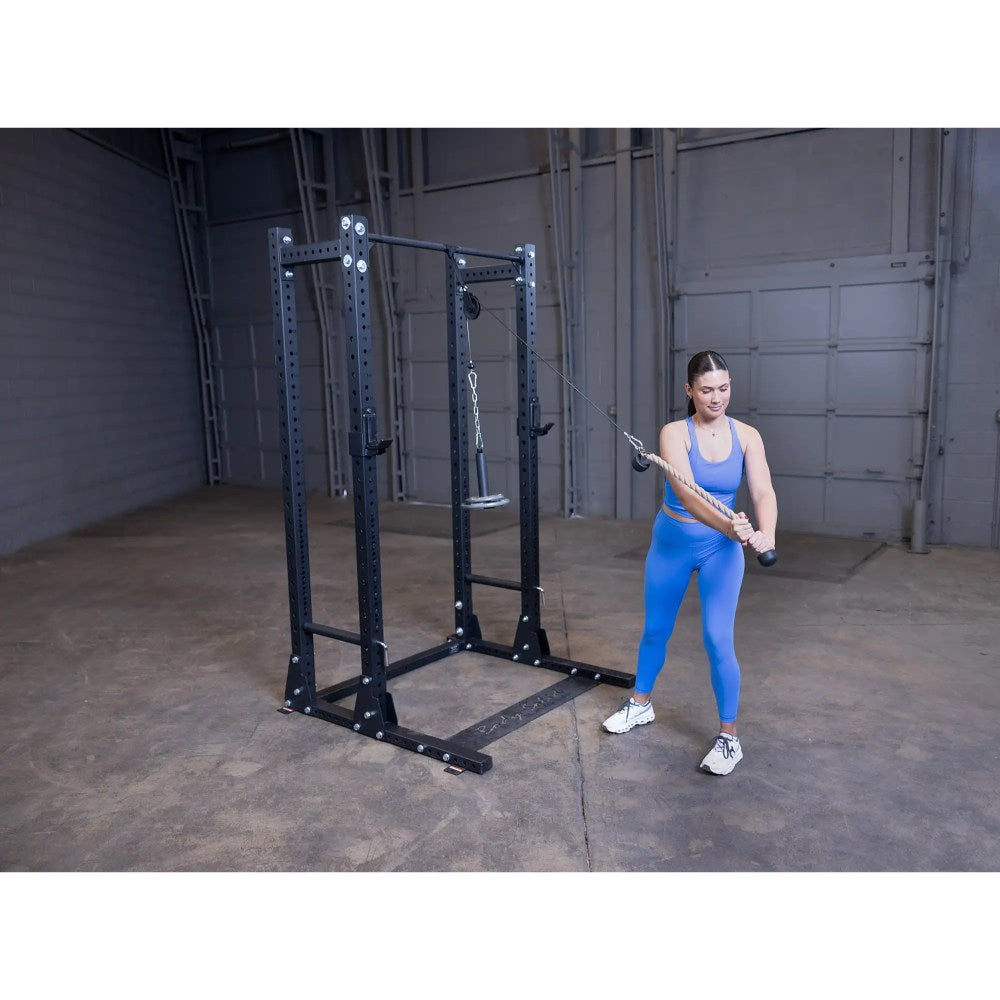 Woman using a black cable machine in a gym, wearing a blue workout outfit.