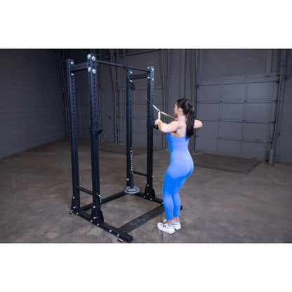 Woman in blue workout attire using a black cable machine in a gym for strength training.