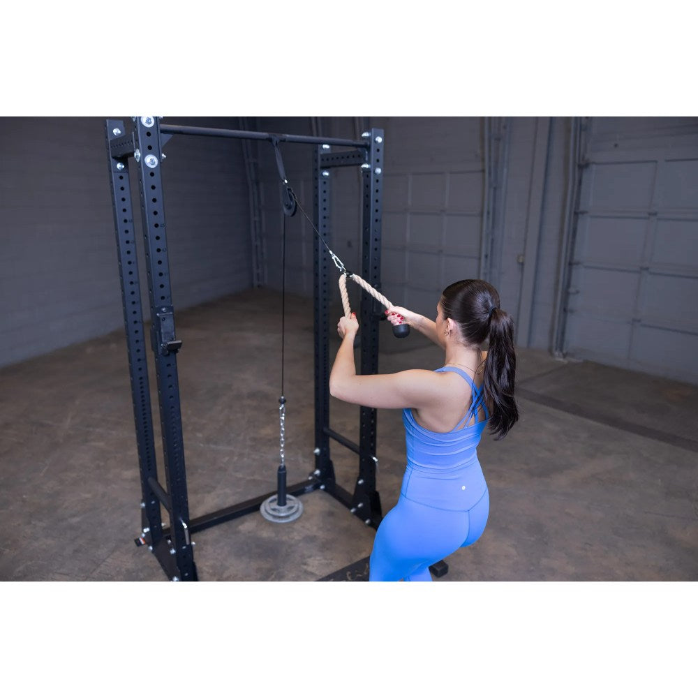 Woman using cable pulley machine in gym, wearing blue workout outfit.