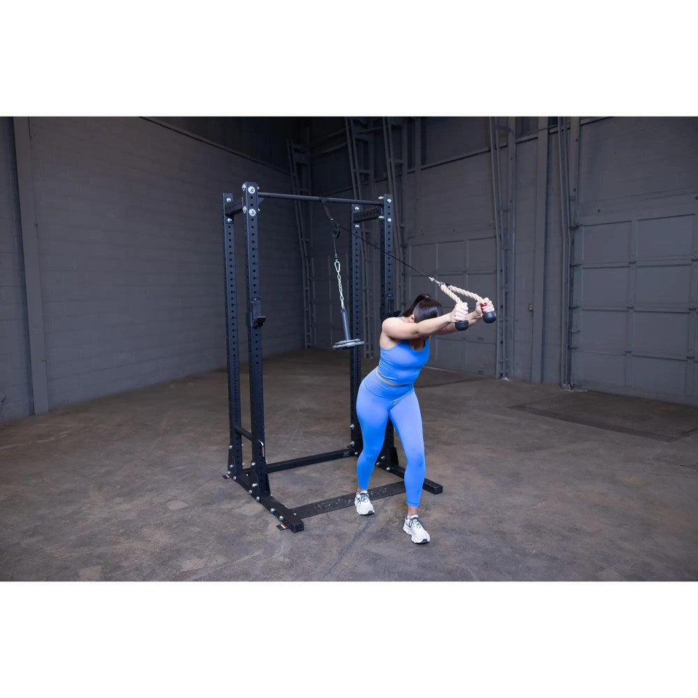Woman in blue workout gear using a cable machine for tricep exercises in a gym.