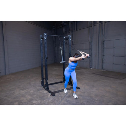 Woman in blue workout gear using a cable machine for tricep exercises in a gym.