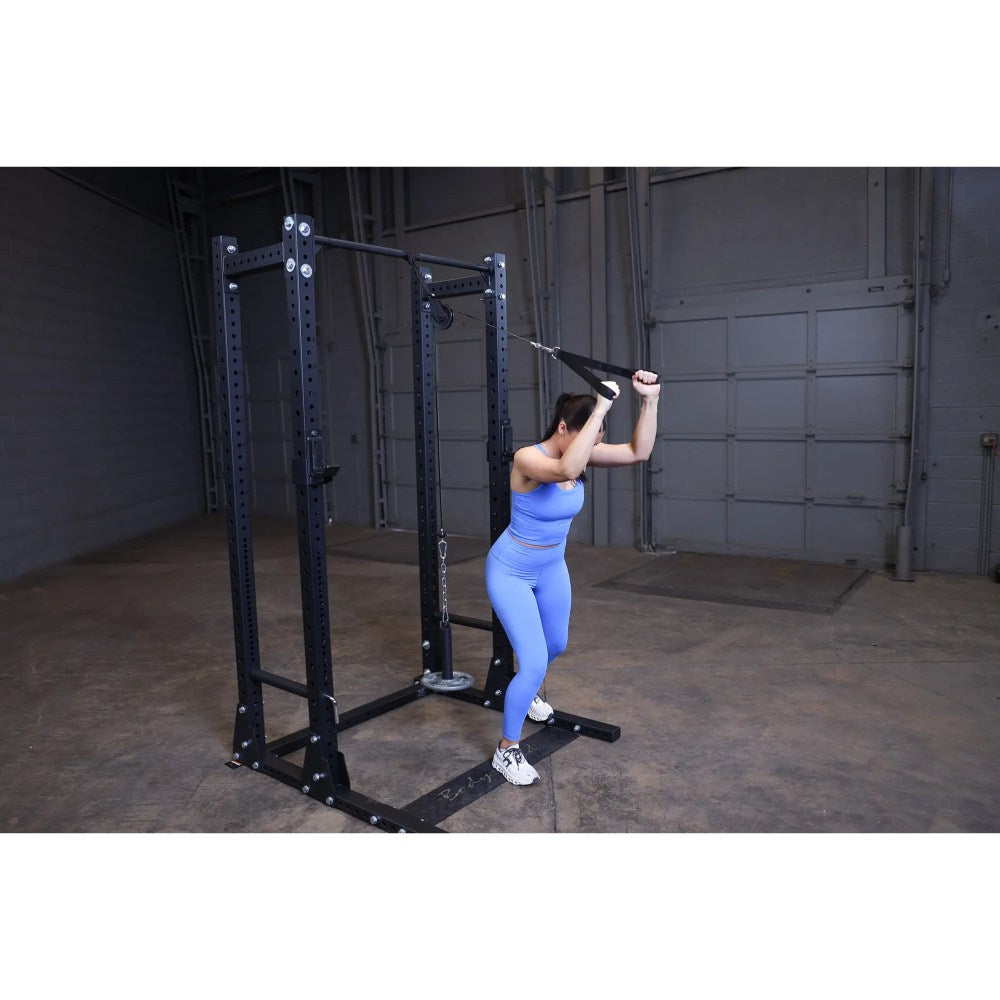 Woman in blue workout outfit using cable machine for tricep exercises in a gym.