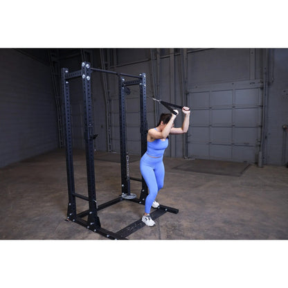 Woman in blue workout outfit using cable machine for tricep exercises in a gym.