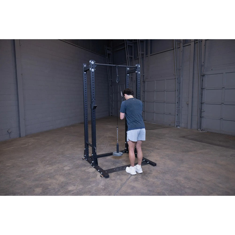 Man exercising on black cable machine in a gym.