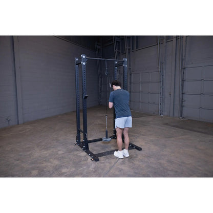 Man exercising on black cable machine in a gym.