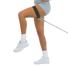 Woman exercising with resistance band on thigh, wearing white sneakers and gray shorts, focusing on leg workout.