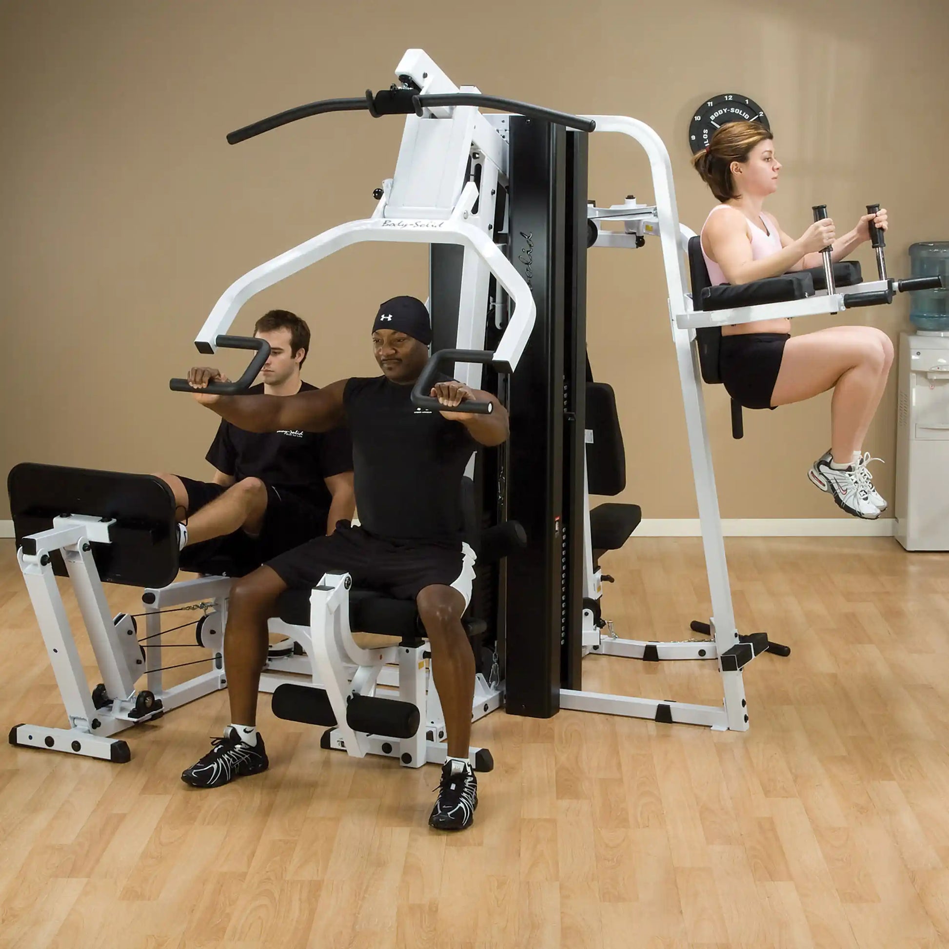 People using Body-Solid home gym equipment for upper body workout in a fitness room.