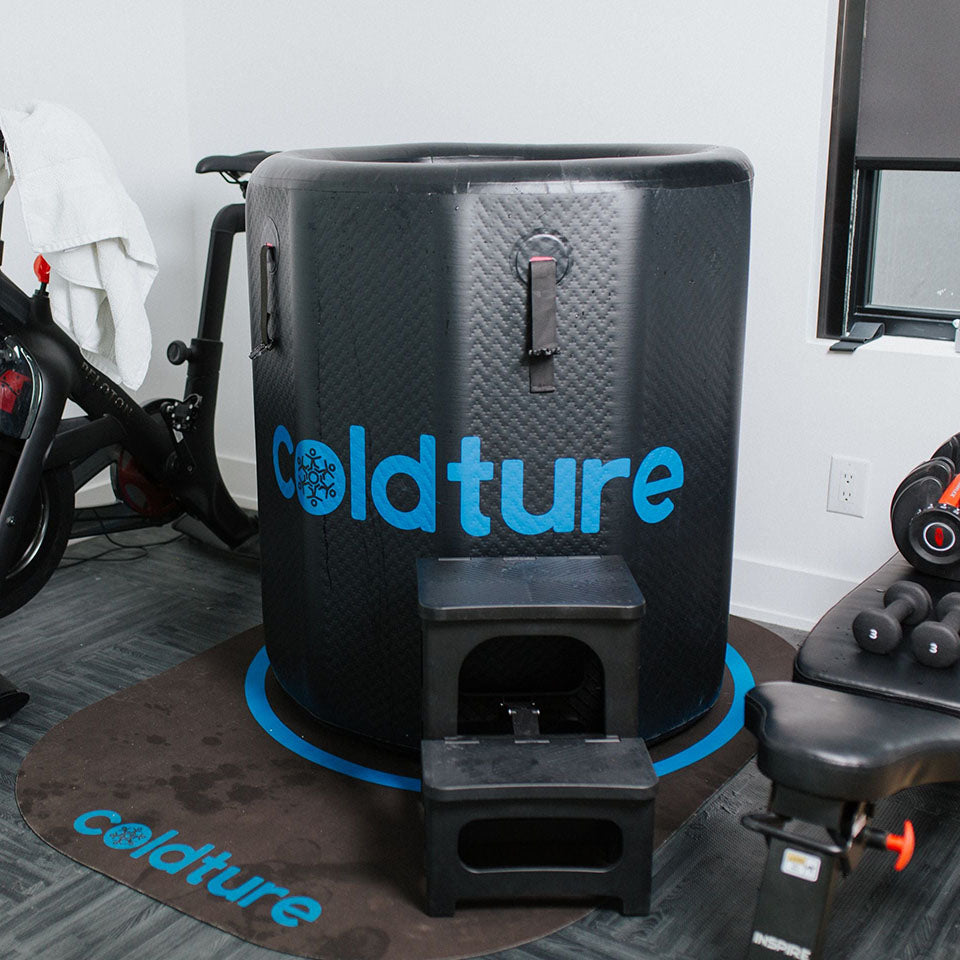 Coldture Barrel + Chiller Pro in a fitness area, featuring a black cold therapy barrel with the Coldture logo, steps for access, and exercise equipment nearby.