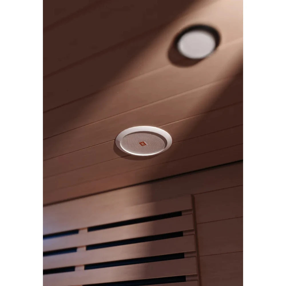 JBL ceiling speaker with white grille installed in wooden sauna ceiling.