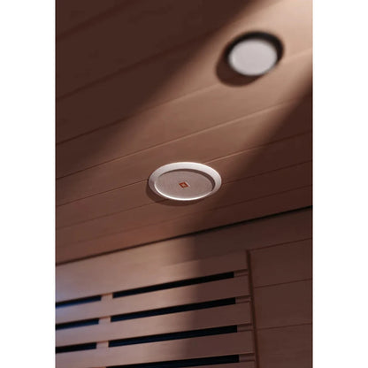 JBL ceiling speaker with white grille installed in wooden sauna ceiling.