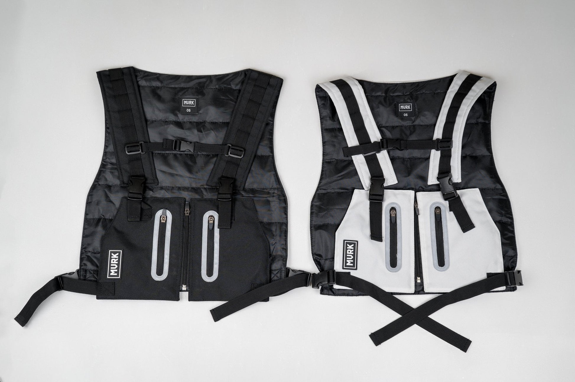 Two MVRK life jackets side by side: black and white, with zippers and straps.