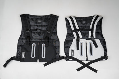 Two MVRK life jackets side by side: black and white, with zippers and straps.