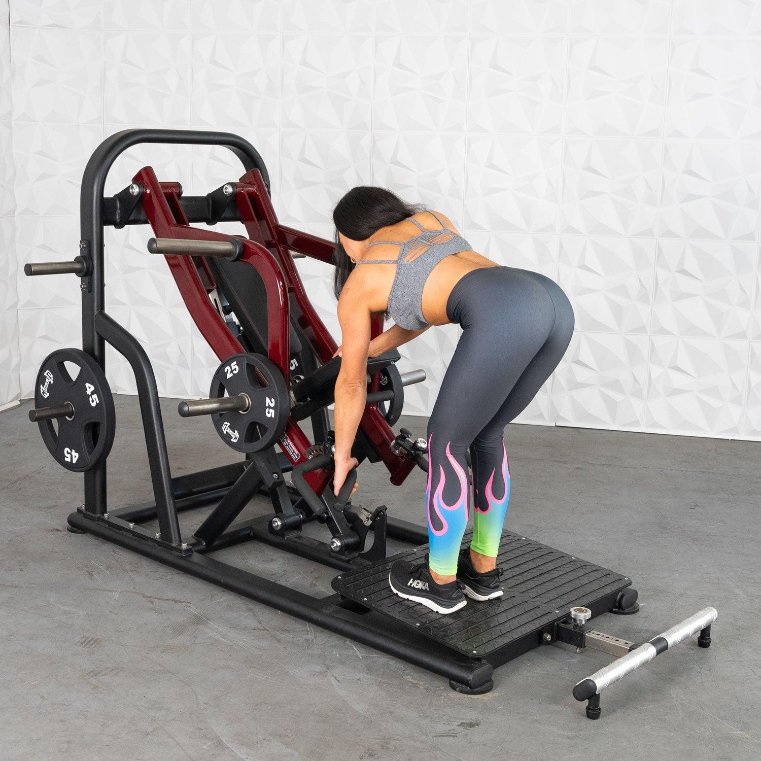 Woman using a leg press machine with colorful flame leggings in a gym setting.
