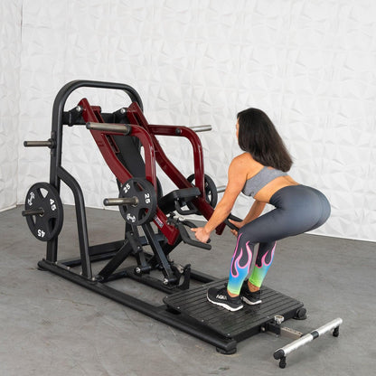 Woman using a squat machine with red handles in colorful leggings.