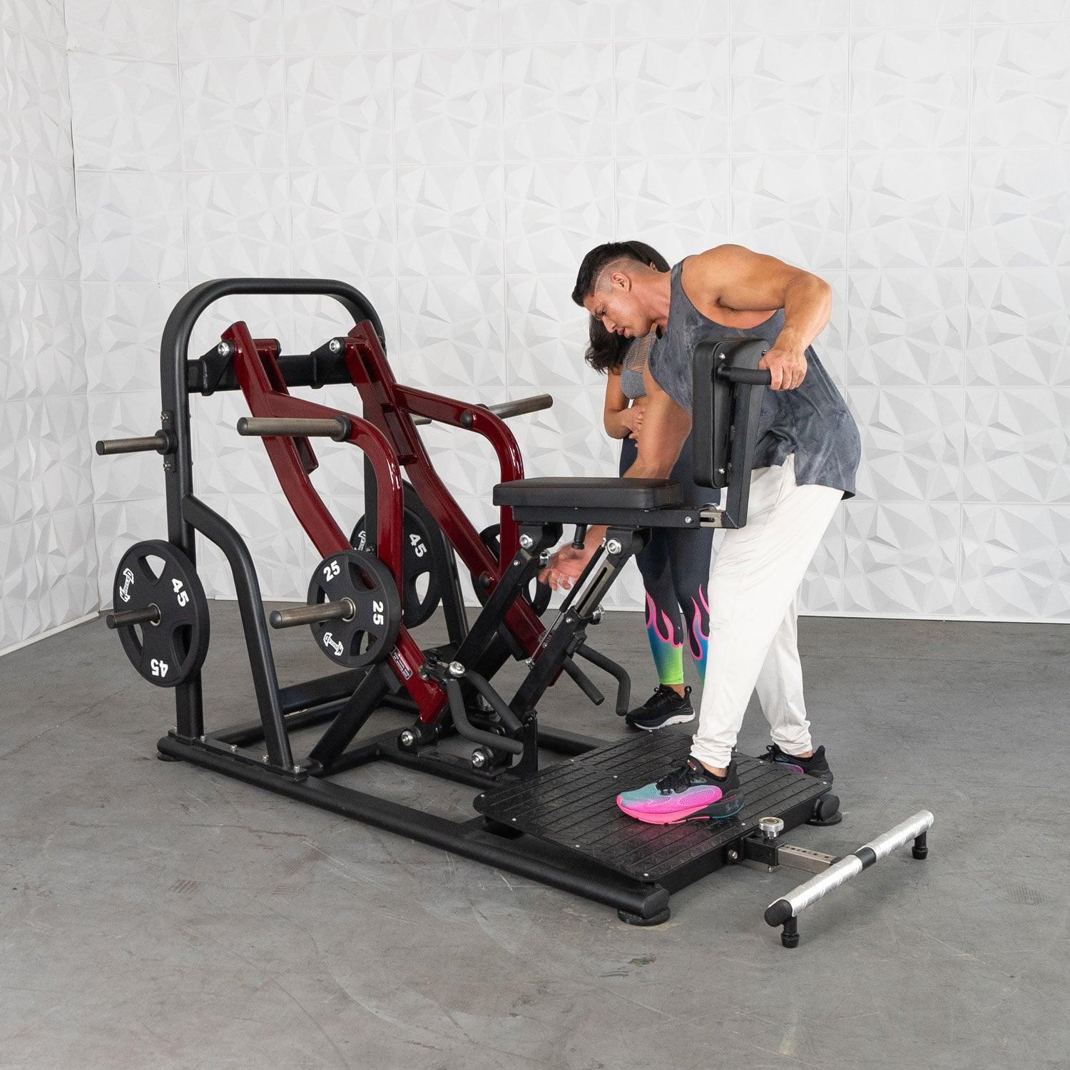 Man adjusting seated calf raise machine with red frame in gym.