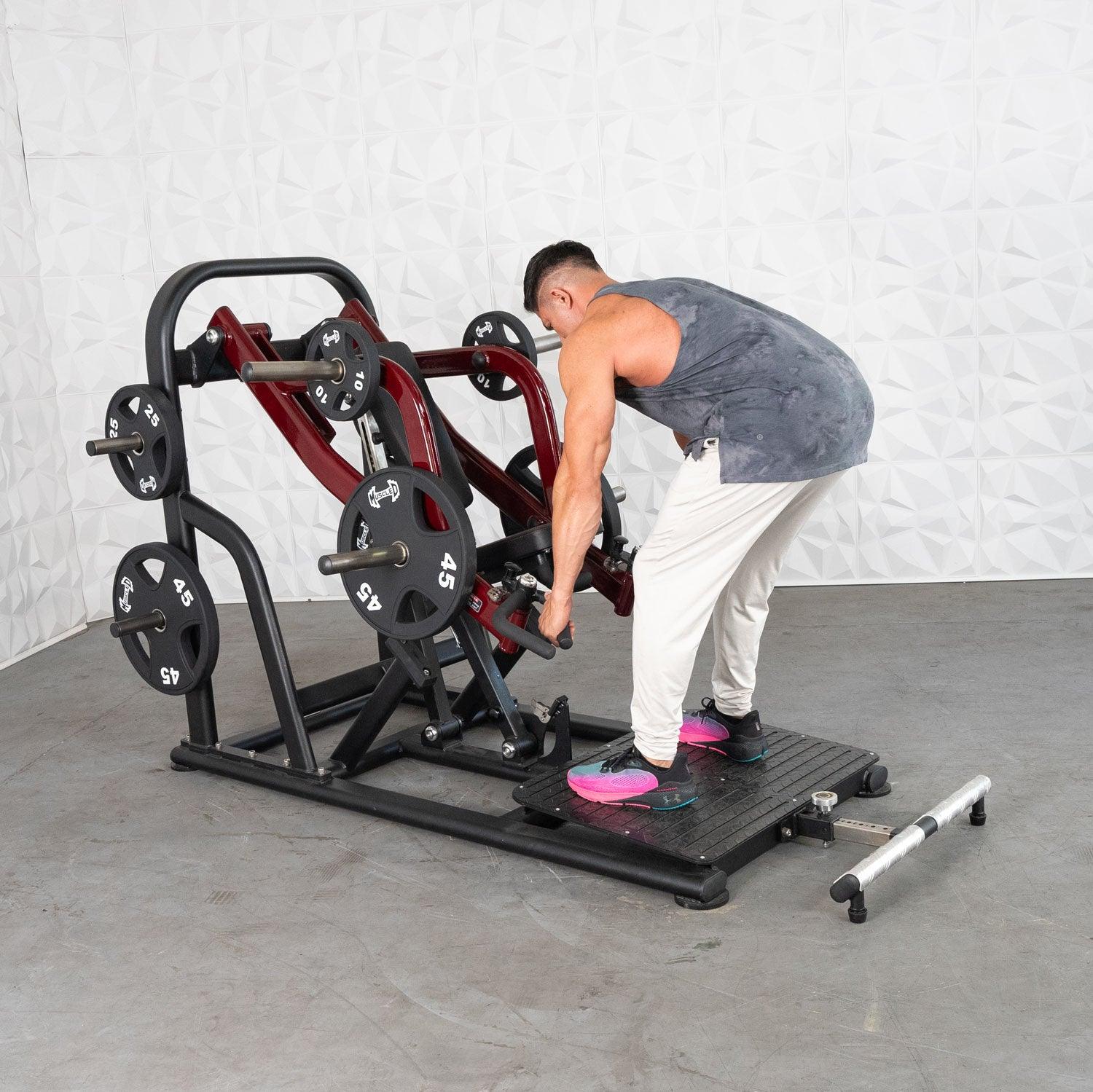 Man using a red plate-loaded row machine in a gym.