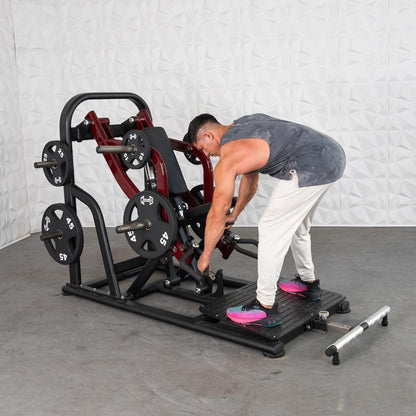 Man adjusting weights on a red leg press machine in a gym.