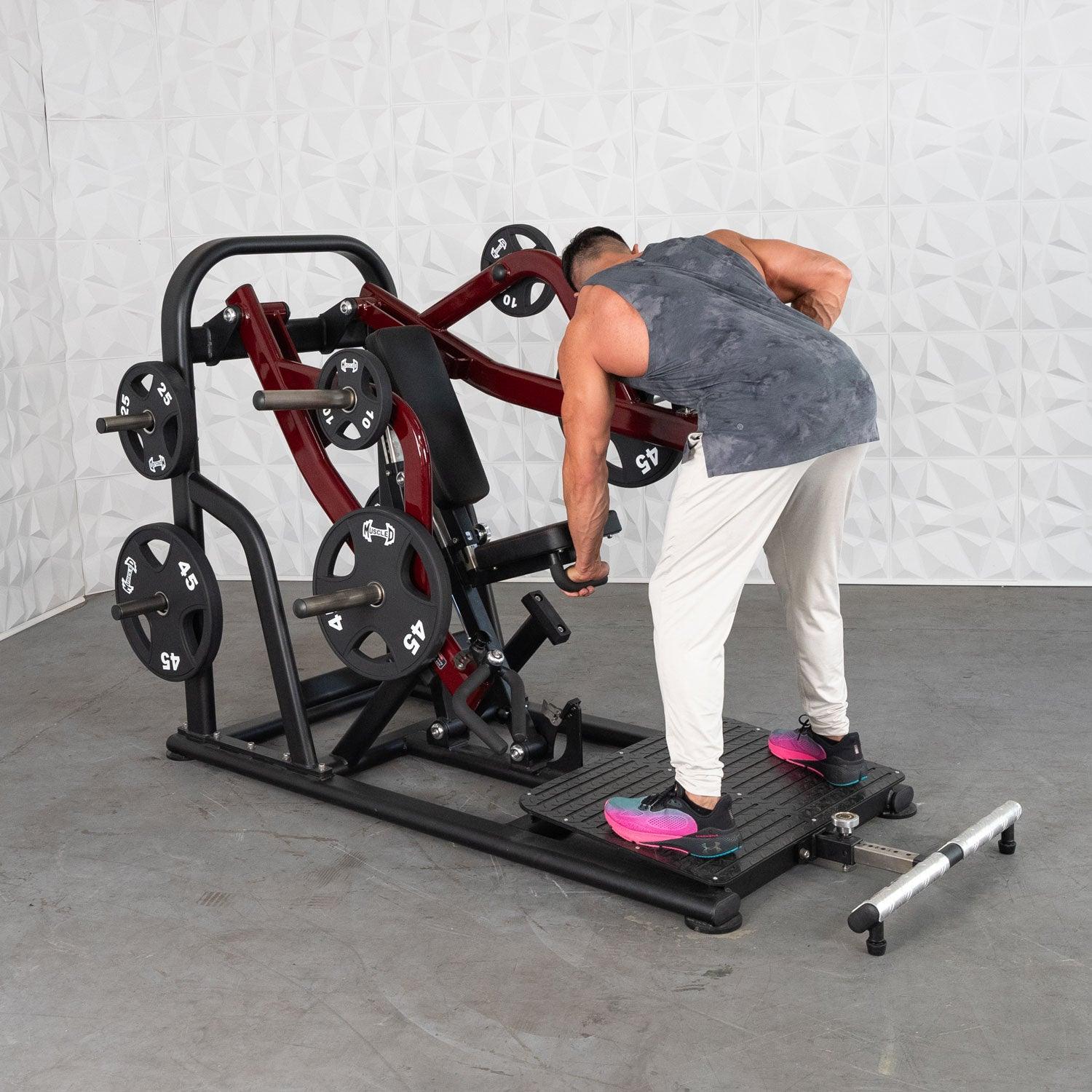 Man using a red plate-loaded back extension machine in a gym.
