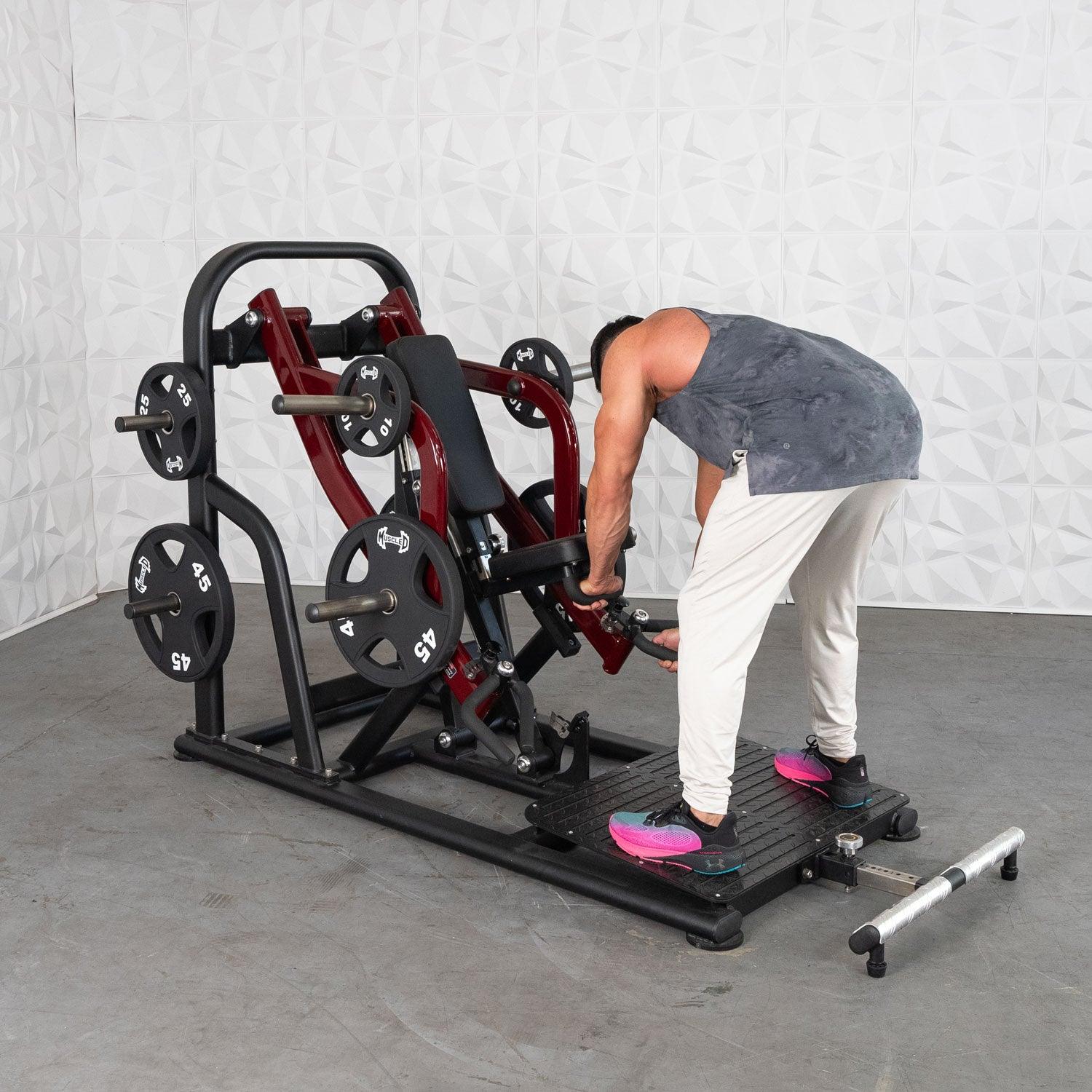 Man using a plate-loaded back row machine with red frame and 45 lb weights in a gym.