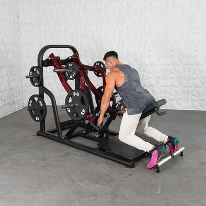 Man using a plate-loaded row machine in a gym, wearing a gray tank top and colorful sneakers.