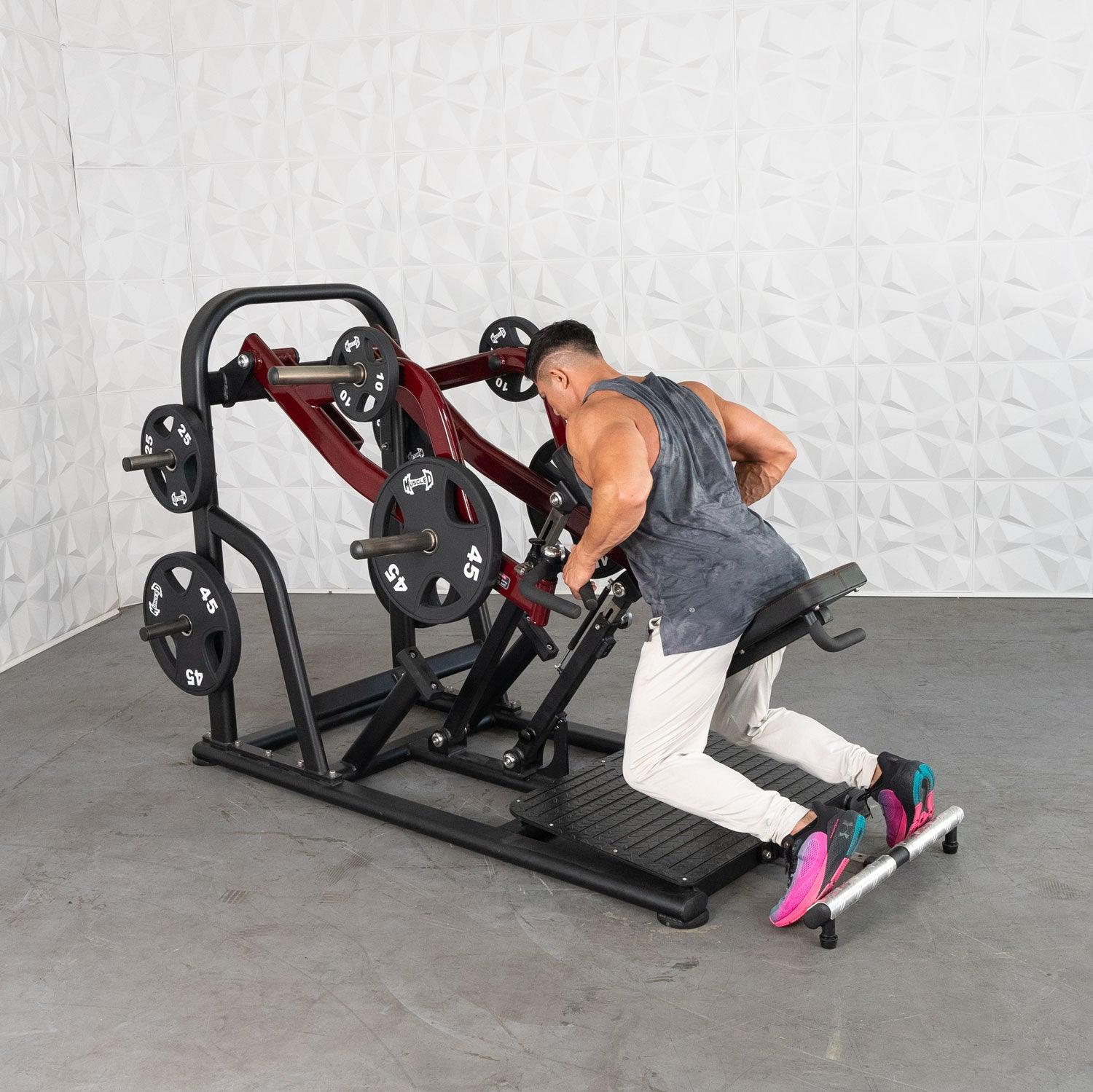 Man using Plate loaded row machine with red frame and weight plates in a gym setting.