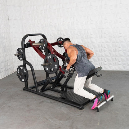 Man using Plate loaded row machine with red frame and weight plates in a gym setting.