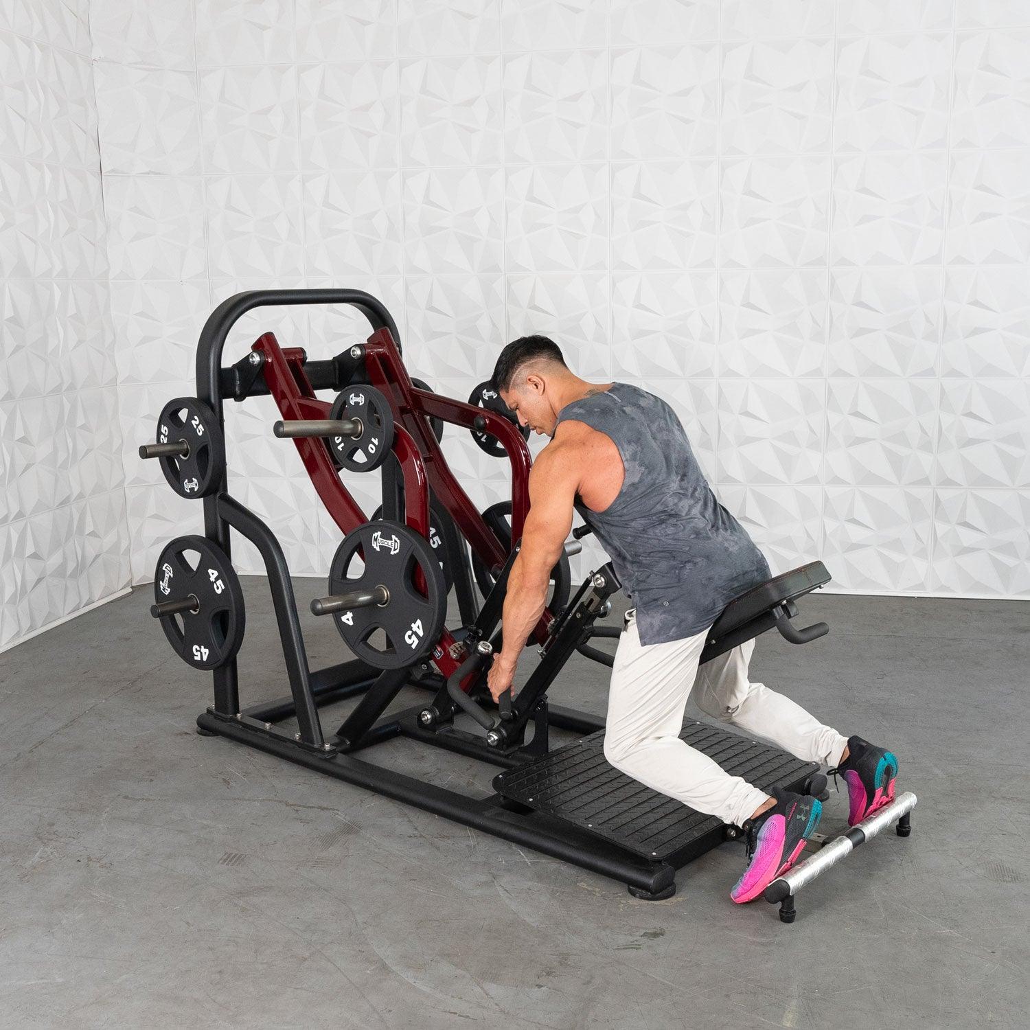 Man using a Plate loaded row machine with red accents for weight training.