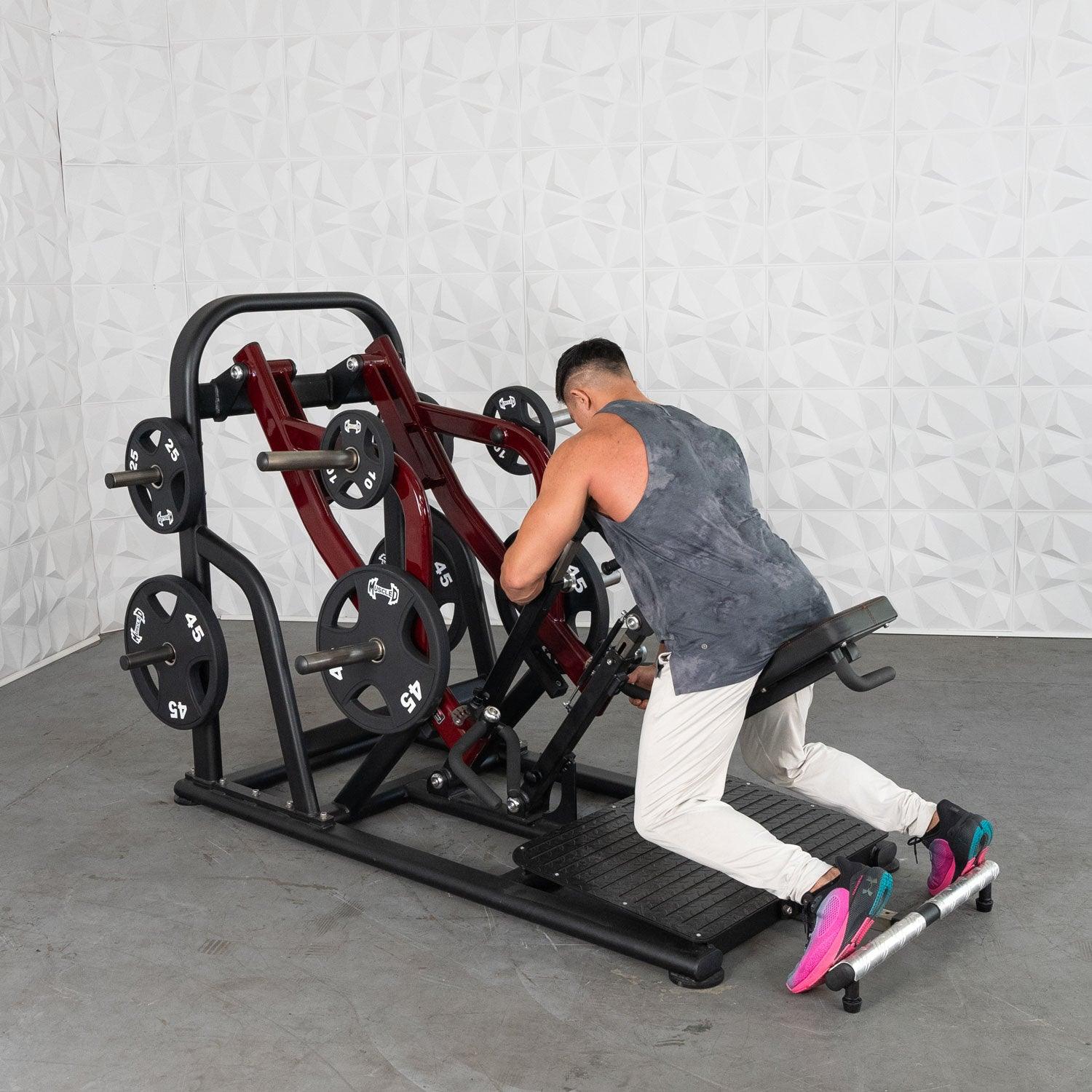 Man using a Plate loaded row machine with multiple weight plates in a gym.
