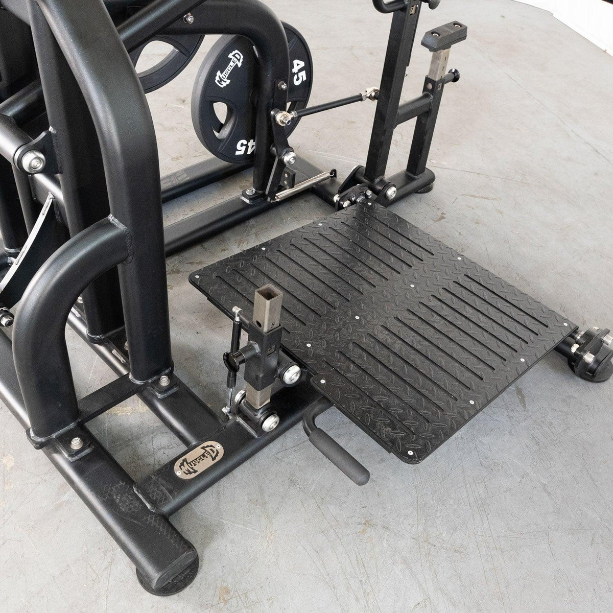 Gym equipment with a diamond-pattern metal foot plate and weight plate.