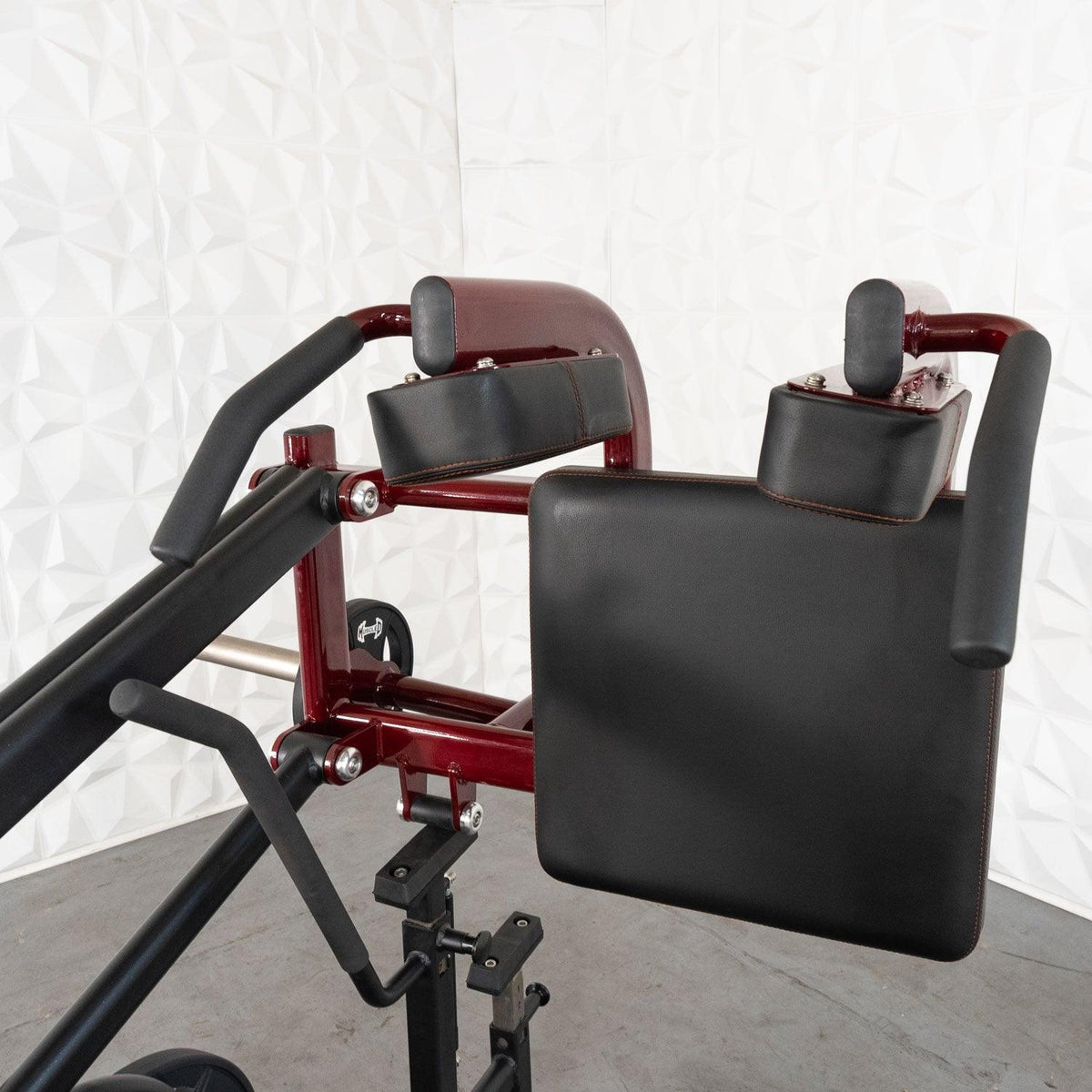 Red exercise machine with padded backrest and black pads.