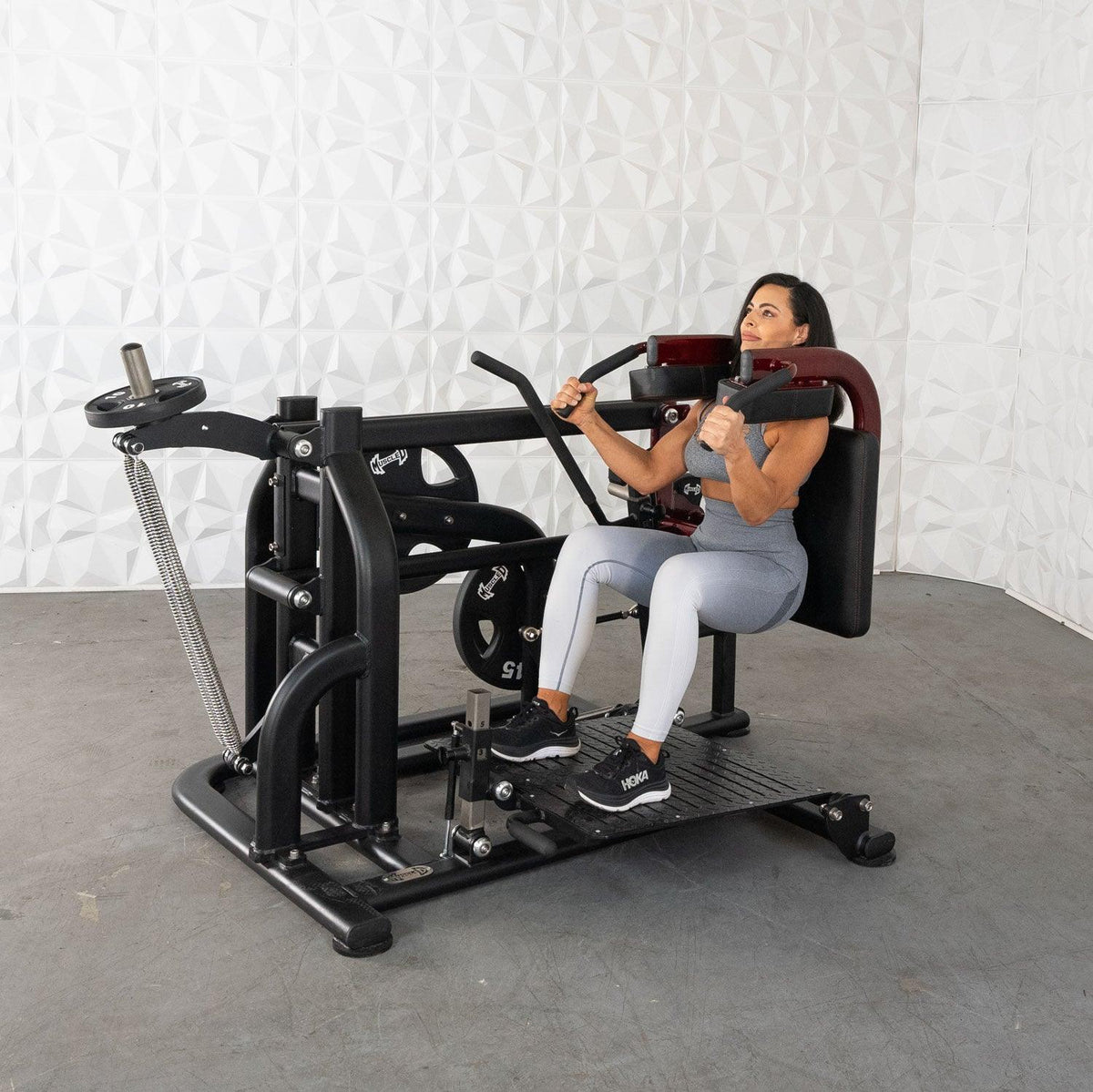 Woman using a seated leg extension/press fitness machine in gym.