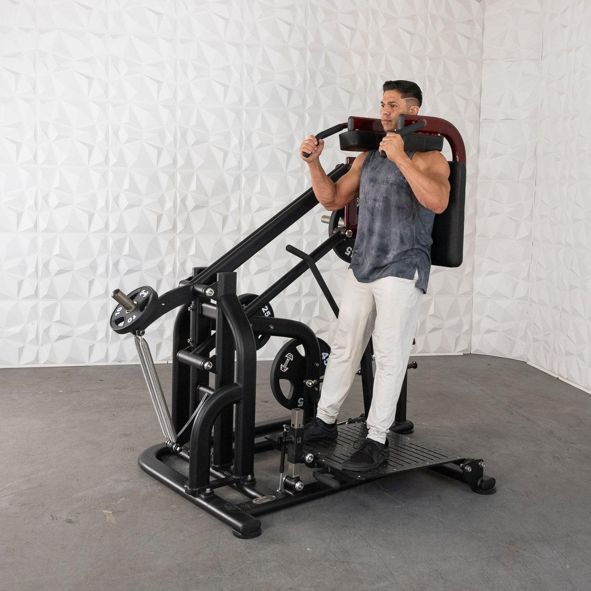 Man using a leg-press machine in a white-tiled gym room.
