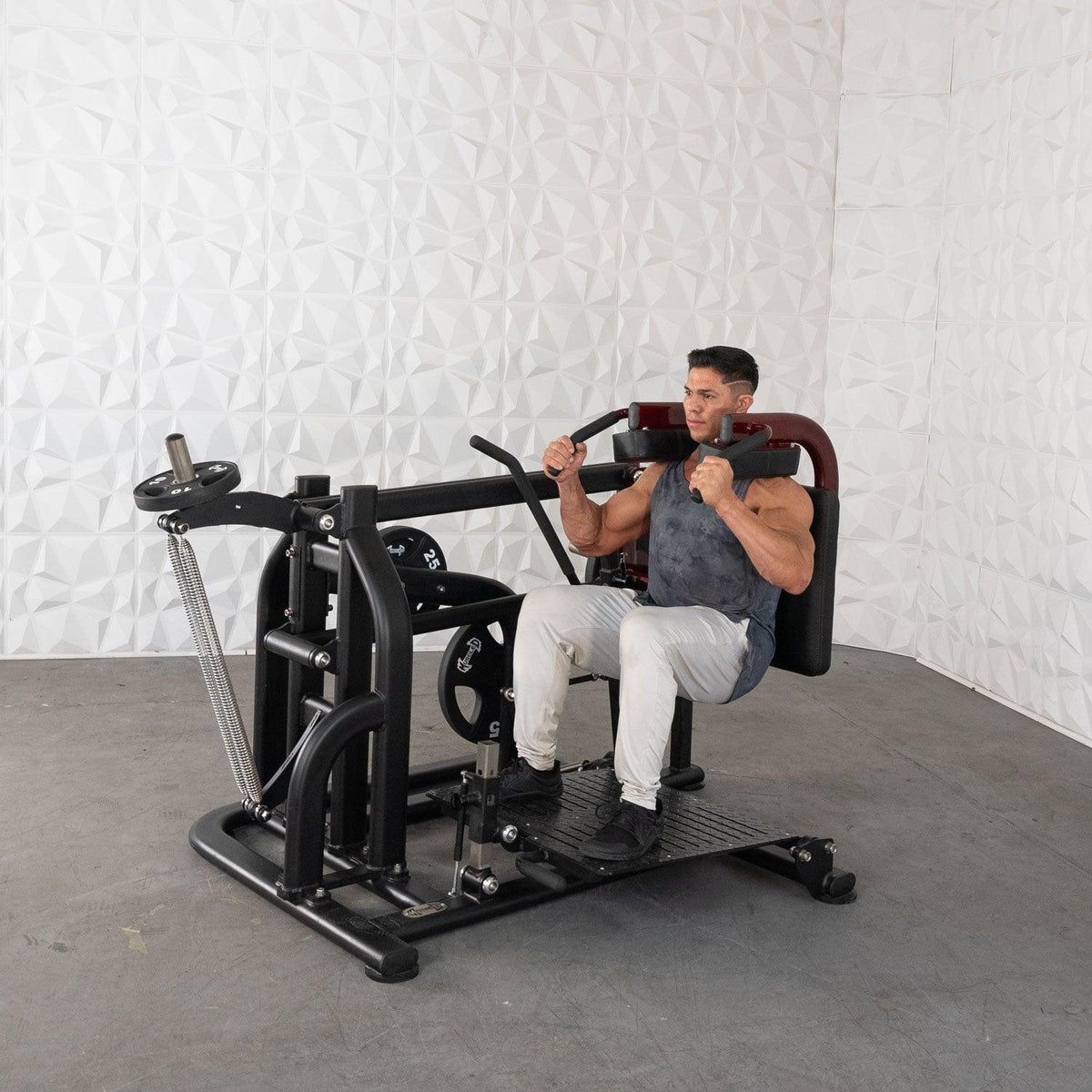 Man working out on seated chest press machine in gym.