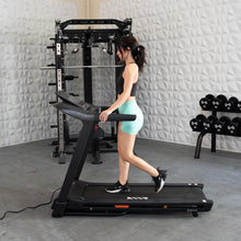 Woman running on a treadmill in a modern gym with free weights.
