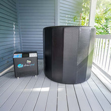 Dreampod Cold Plunge Barrel Flex positioned on a wooden deck next to its control unit, with a blue wall in the background.