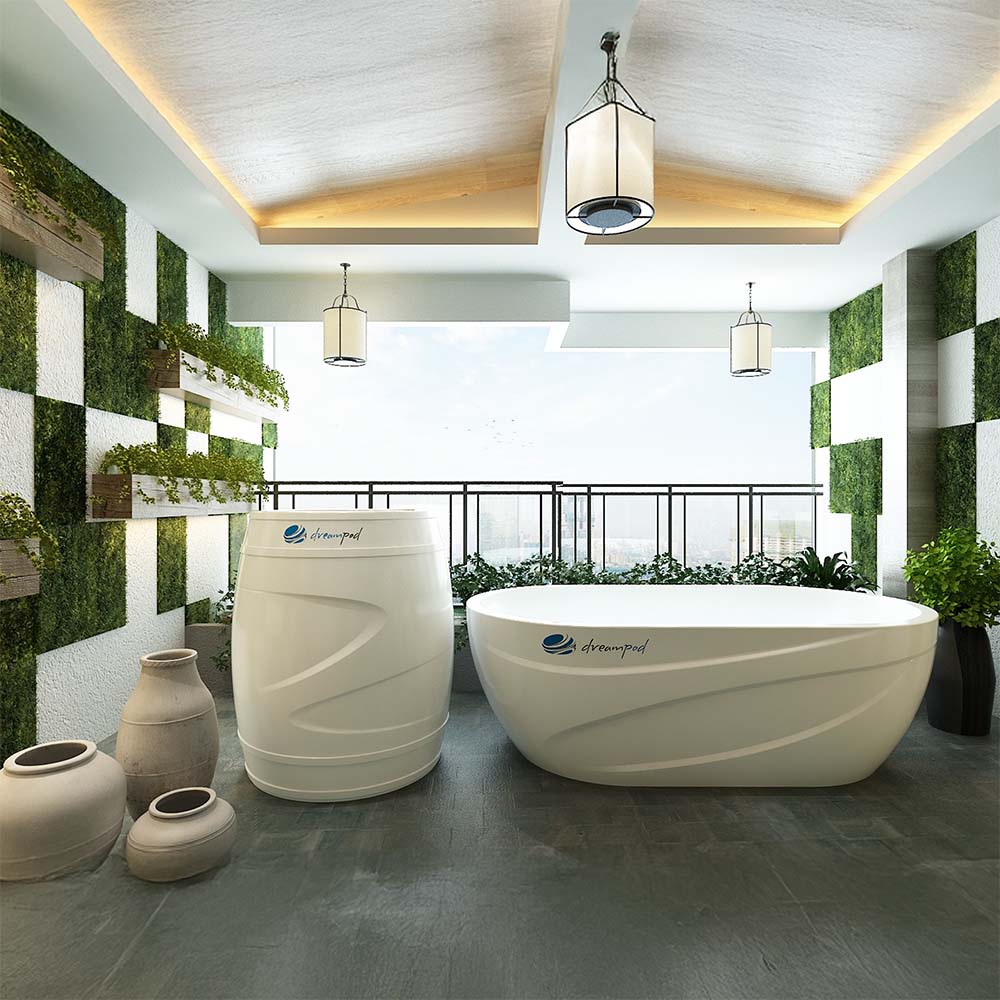 A modern outdoor space featuring the Dreampod Cold Plunge Barrel alongside a sleek white soaking tub, surrounded by greenery and decorative planters, with stylish lighting fixtures above.