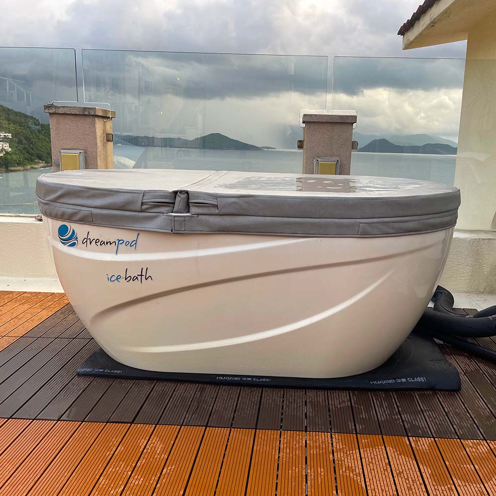 Dreampod Commercial Cold Plunge ice bath positioned on a wooden deck with a scenic view of the ocean and cloudy skies.