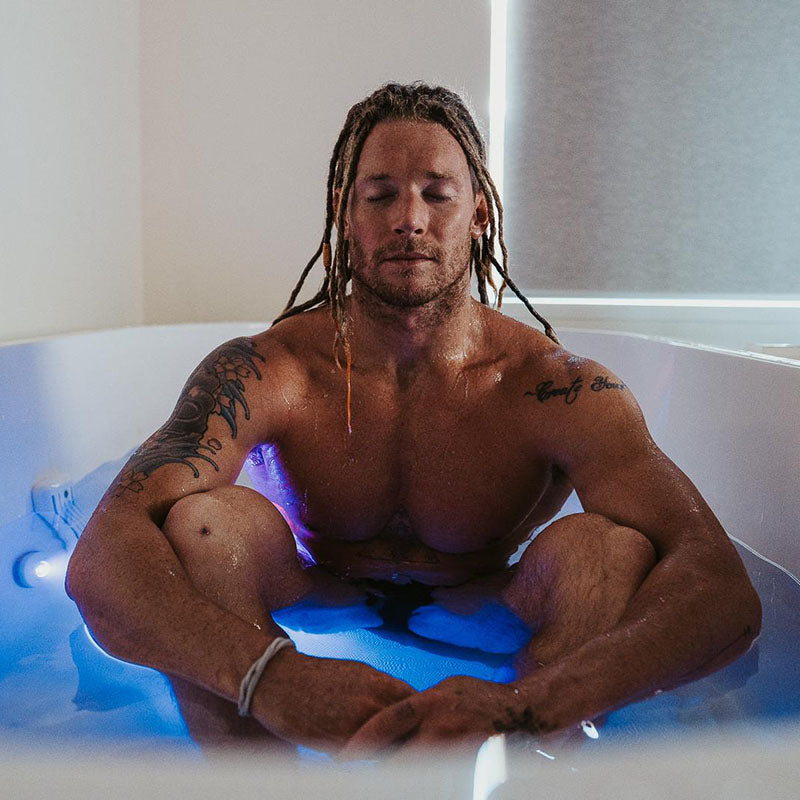 Person meditating in a Dreampod Commercial Cold Plunge, with blue lighting and a serene atmosphere.