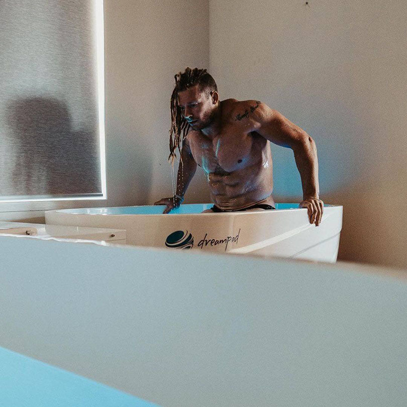 A person with long hair is stepping into a Dreampod Commercial Cold Plunge, showcasing the sleek design of the plunge in a well-lit indoor setting.