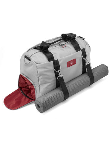 Gray duffel bag with black straps and a rolled gray yoga mat.