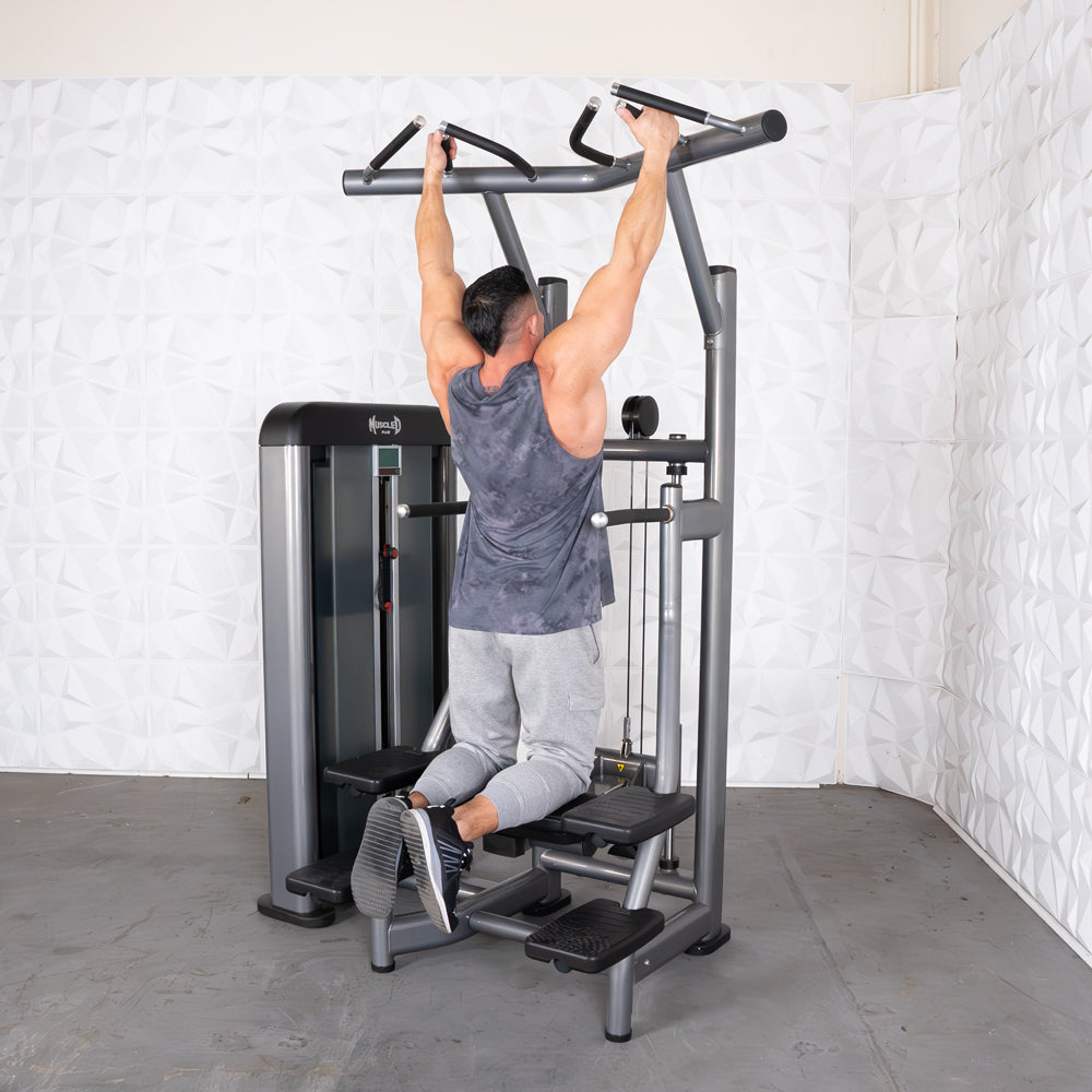 Man using a gray assisted pull-up machine in a gym.