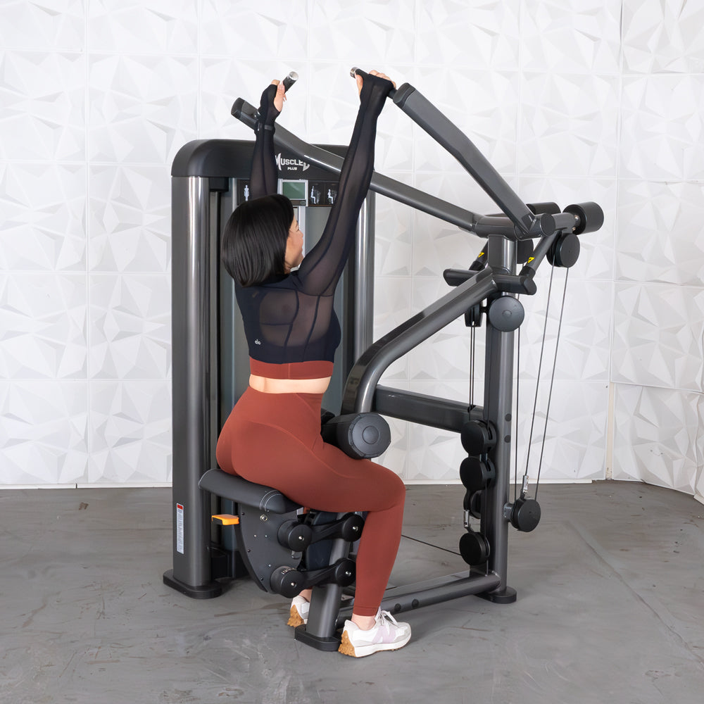Woman using Muscle Plus lat pulldown machine in red leggings.