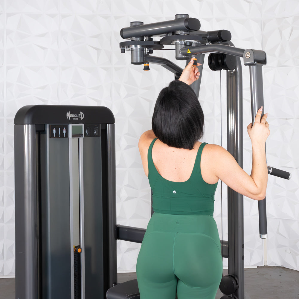 Woman in green outfit using Elite-Plus Pec-Rear Delt machine at gym.