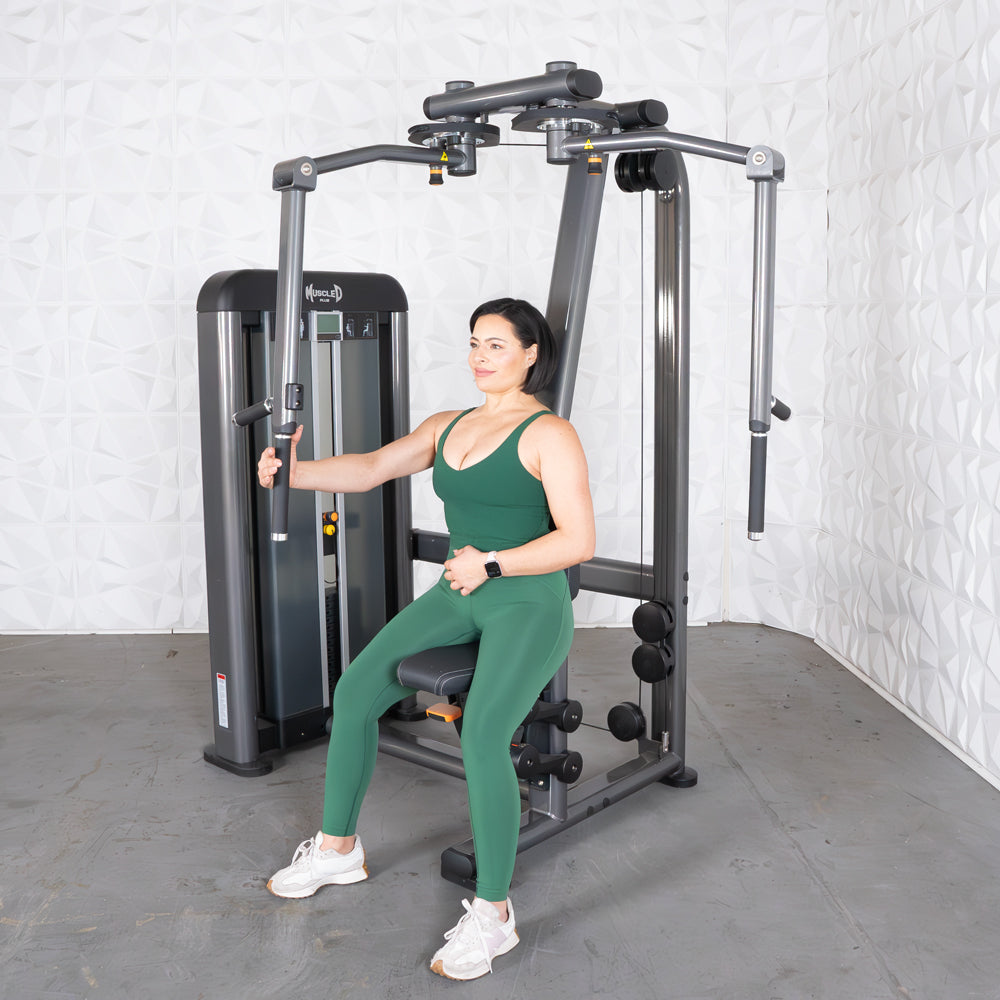 Woman in green workout outfit using Elite Plus pec/rear delt machine.